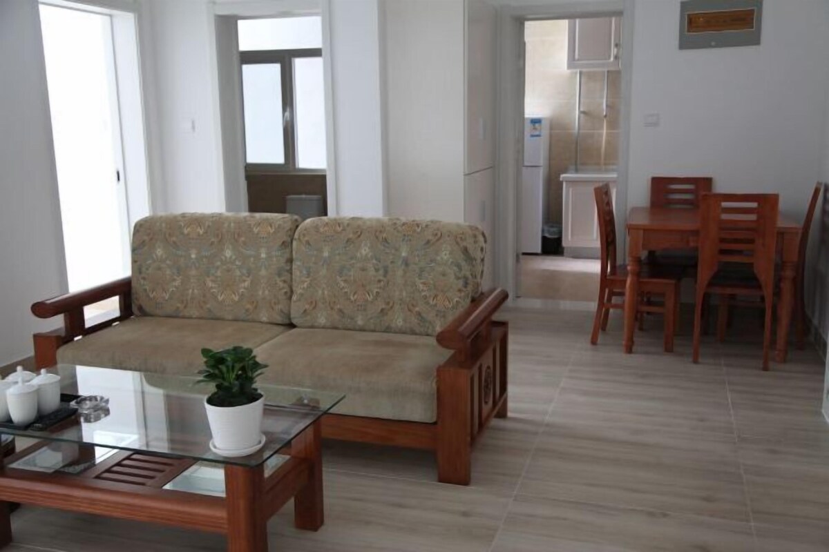 Una sala de estar con sofá, una mesa de centro de vidrio y un comedor con sillas de madera y una mesa.