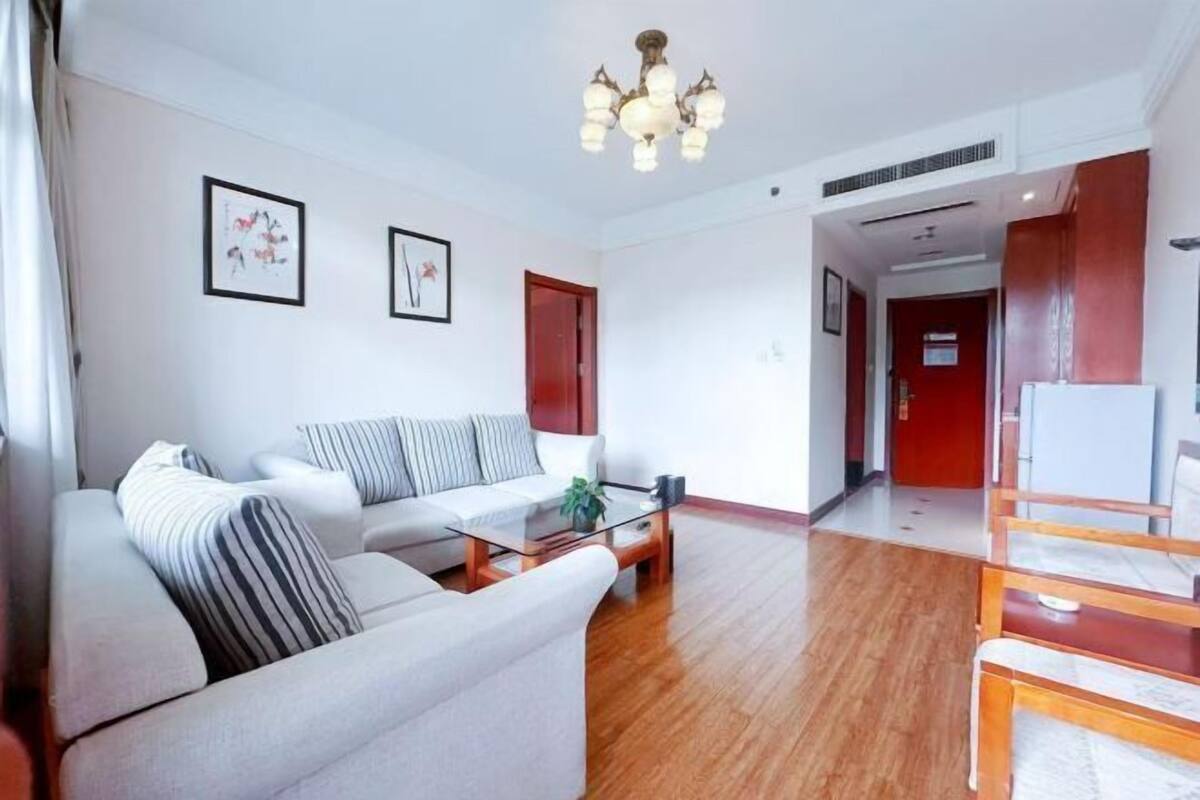 Een moderne woonkamer met een bank, een glazen salontafel en een kroonluchter.