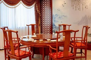 A traditional round table with chairs, a decorative screen, and a mural on the wall. - China Magnetic Mountain Springs Park (Yantai)
