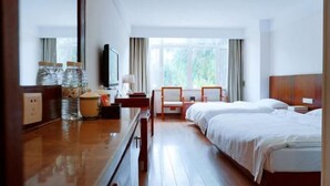 A hotel room with a wooden desk, two beds, a TV, and a window with curtains. - China Magnetic Mountain Springs Park (Yantai)