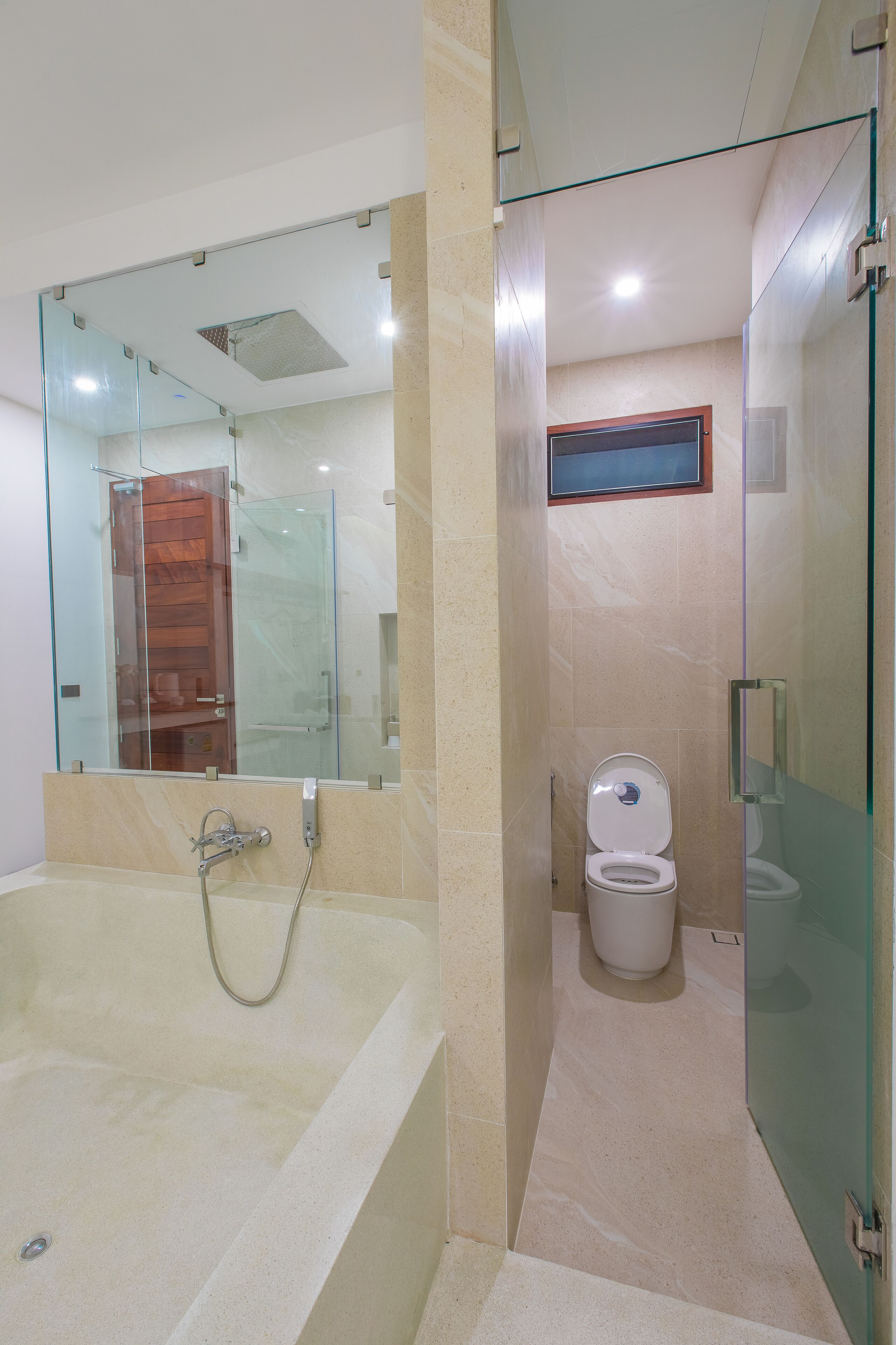 A modern bathroom with a glass-enclosed shower, a separate toilet, and a large bathtub.