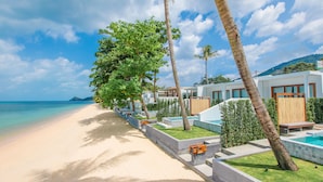 A beachfront hotel with a pool, palm trees, and a clear view of the ocean. - White Whale Beachfront Pool Villa (Koh Samui)