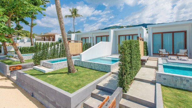 A modern resort with multiple swimming pools, palm trees, and a clear blue sky. - White Whale Beachfront Pool Villa (Koh Samui)