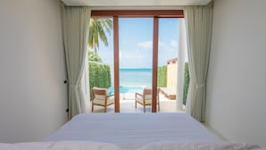 A bedroom with a large bed, a view of a pool and beach, and curtains on the windows. - White Whale Beachfront Pool Villa (Koh Samui)