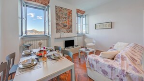 A room with a dining table set for two, a sofa, a TV, and a fireplace. - Incanto Sul Lago: Arona Lakefront Apartment with A/C, Arona, Italy (Arona)