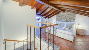 A bedroom with a stone wall, a bed, a nightstand, and a wooden ceiling. - Incanto Sul Lago: Arona Lakefront Apartment with A/C, Arona, Italy (Arona)