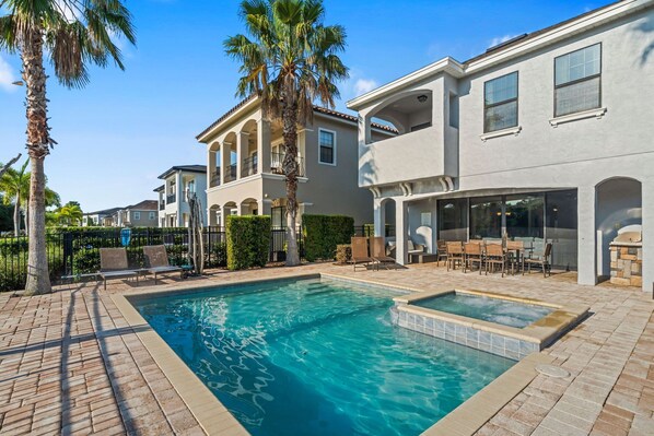 A residential property with a swimming pool, outdoor seating area, and a covered patio.