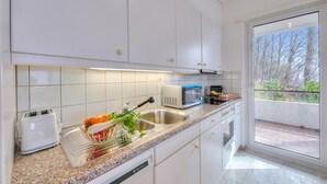 A modern kitchen with white cabinets, a stainless steel sink, a microwave, and a toaster. - Casa Al Bosco With Pool (Lugano)