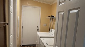 A laundry room with a washing machine and dryer, wooden flooring, and a white door. - Bell, Fl  3/2 home on Suwannee w/boat ramp (Bell)