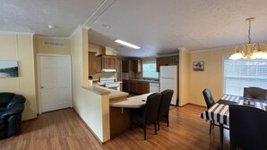 A compact kitchen with wooden cabinets, a central island, and a dining area with a striped tablecloth. - Bell, Fl  3/2 home on Suwannee w/boat ramp (Bell)