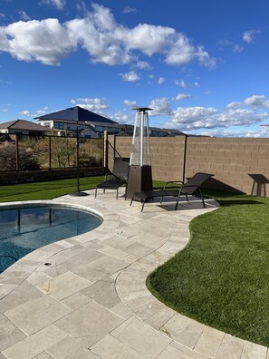 A backyard with a swimming pool, patio furniture, and a tall structure. - Super Bowl Home (Peoria)