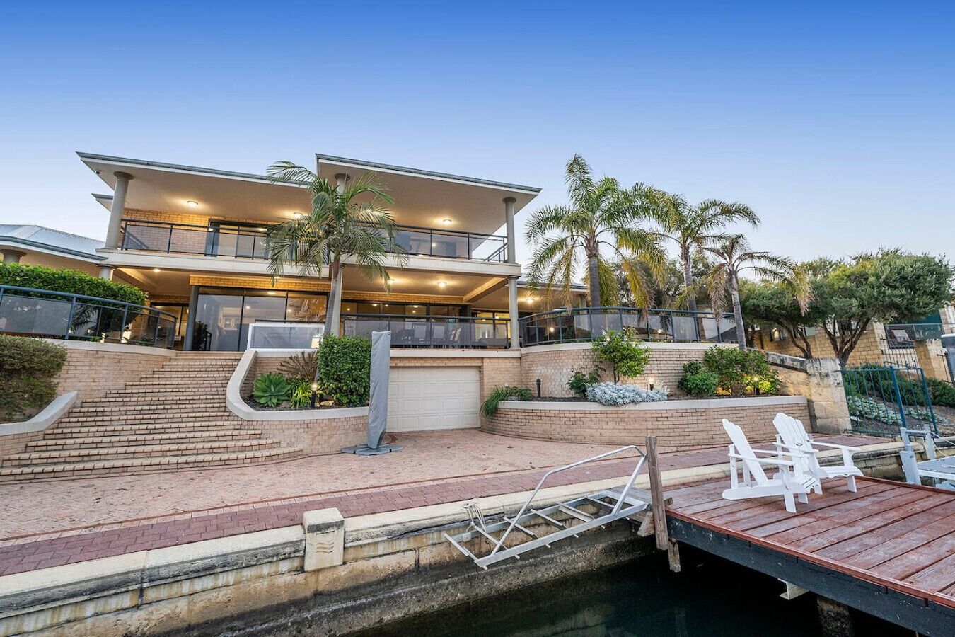 A multi-story house with a dock, outdoor seating, and a staircase leading to the entrance.