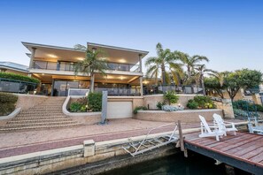 A multi-story house with a dock, outdoor seating, and a staircase leading to the entrance.