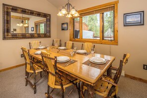 Ein Esszimmer mit einem großen Holztisch, gedeckt für sechs Personen, umgeben von rustikalen Stühlen.