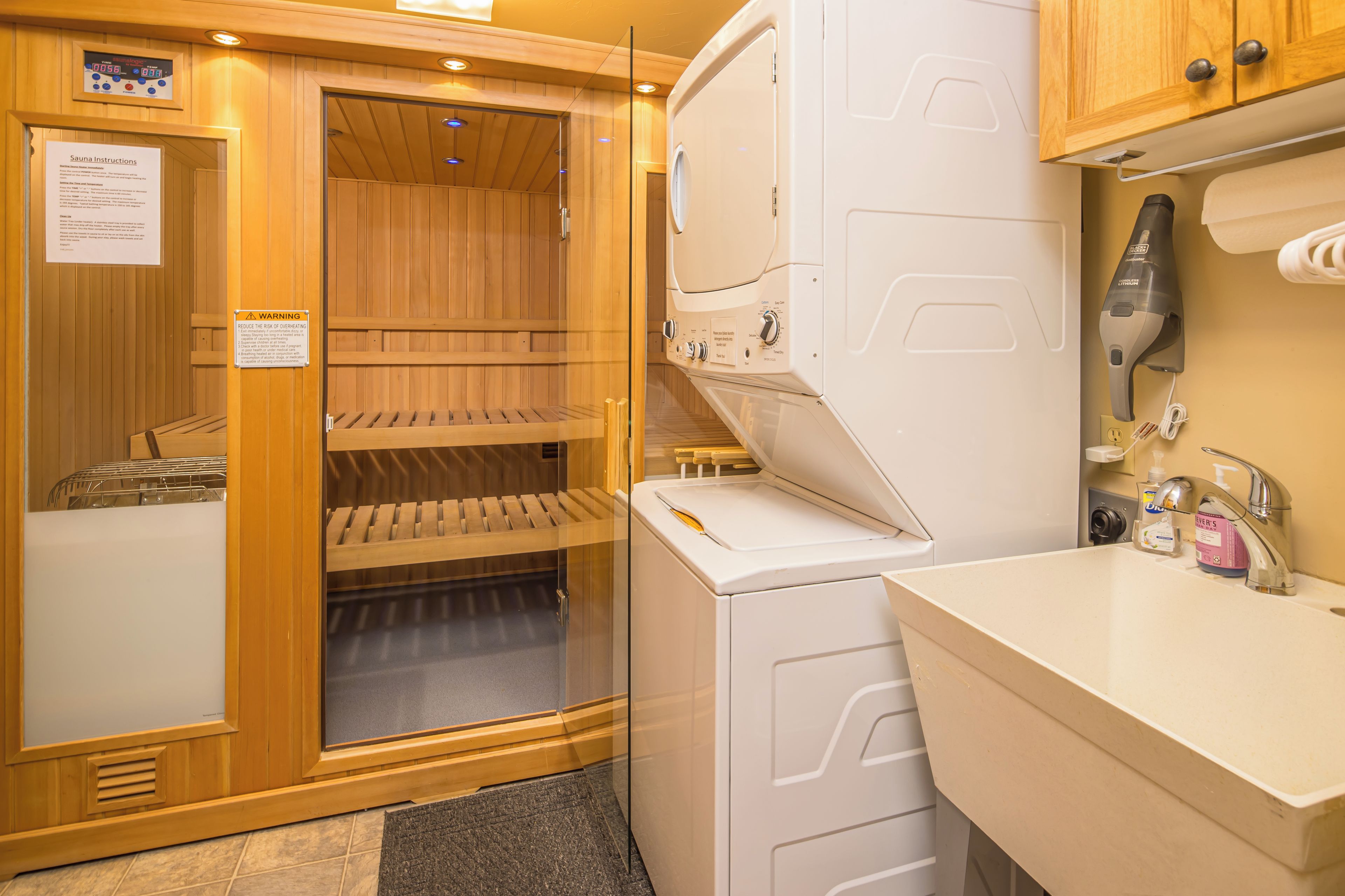 A sauna with wooden walls, a glass door, and a control panel.