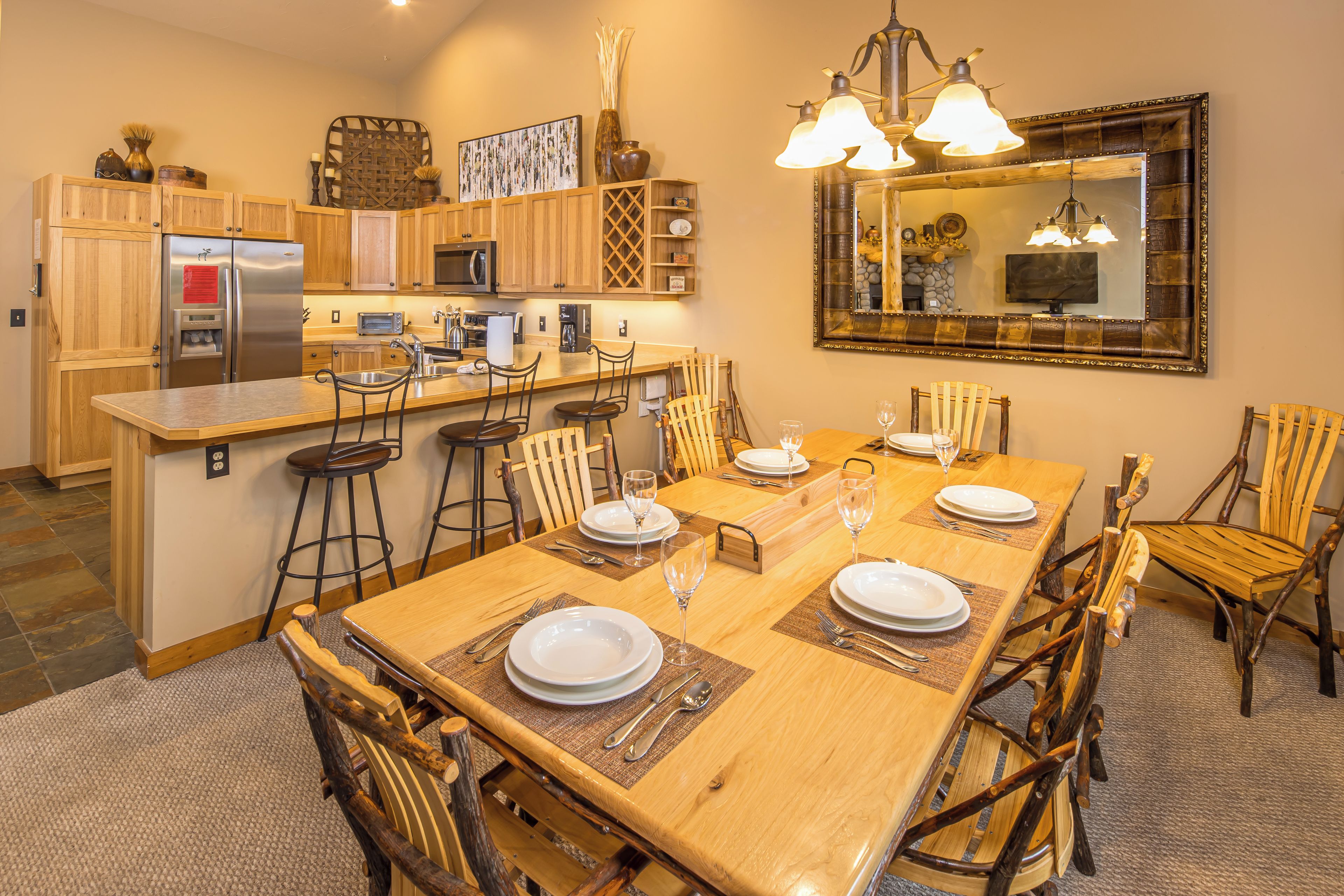 Un coin repas avec une table en bois dressée pour quatre personnes, entourée de chaises au style rustique.
