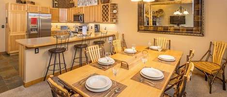 A dining area with a wooden table set for four, surrounded by rustic chairs.