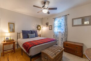 Une chambre à coucher comprenant un lit, une table de chevet, une commode et un ventilateur de plafond.