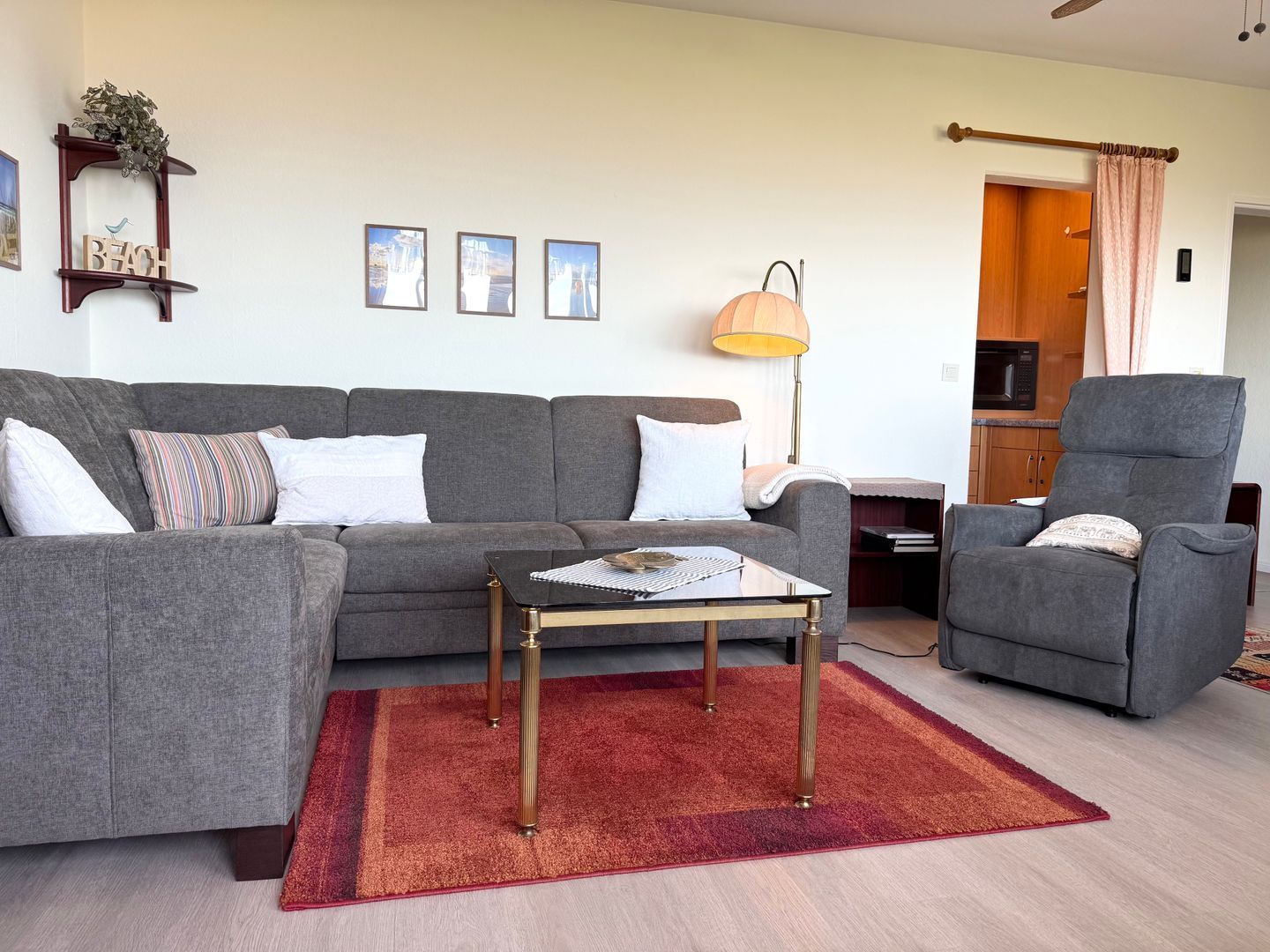 Ein Wohnzimmer mit grauem Sofa, einem passenden Sessel, einem kleinen Couchtisch und einem roten Teppich.