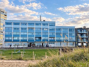 Un edificio de varios pisos con un diseño arquitectónico moderno, que presenta techo plano y ventanas amplias.