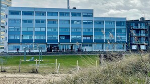 Un edificio moderno de varios pisos con techo plano, amplias ventanas y una entrada visible con área cubierta.