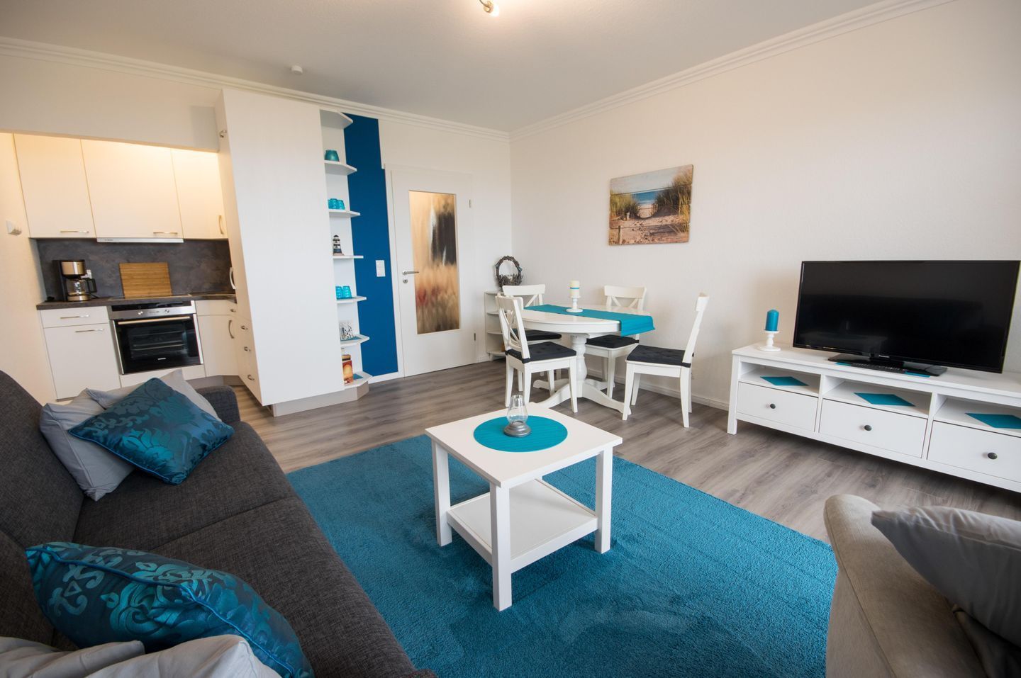 Ein modernes Wohnzimmer mit einer Couch, einem Couchtisch, einem Fernseher und einem Essbereich mit Stühlen und einem Tisch.