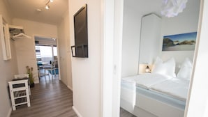 Ein Hotelzimmer mit Bett, Nachttisch, Wand-Fernseher und einem Gemälde.