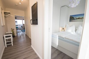 Habitación de hotel con cama, mesita de noche, televisor empotrado en la pared y un cuadro.
