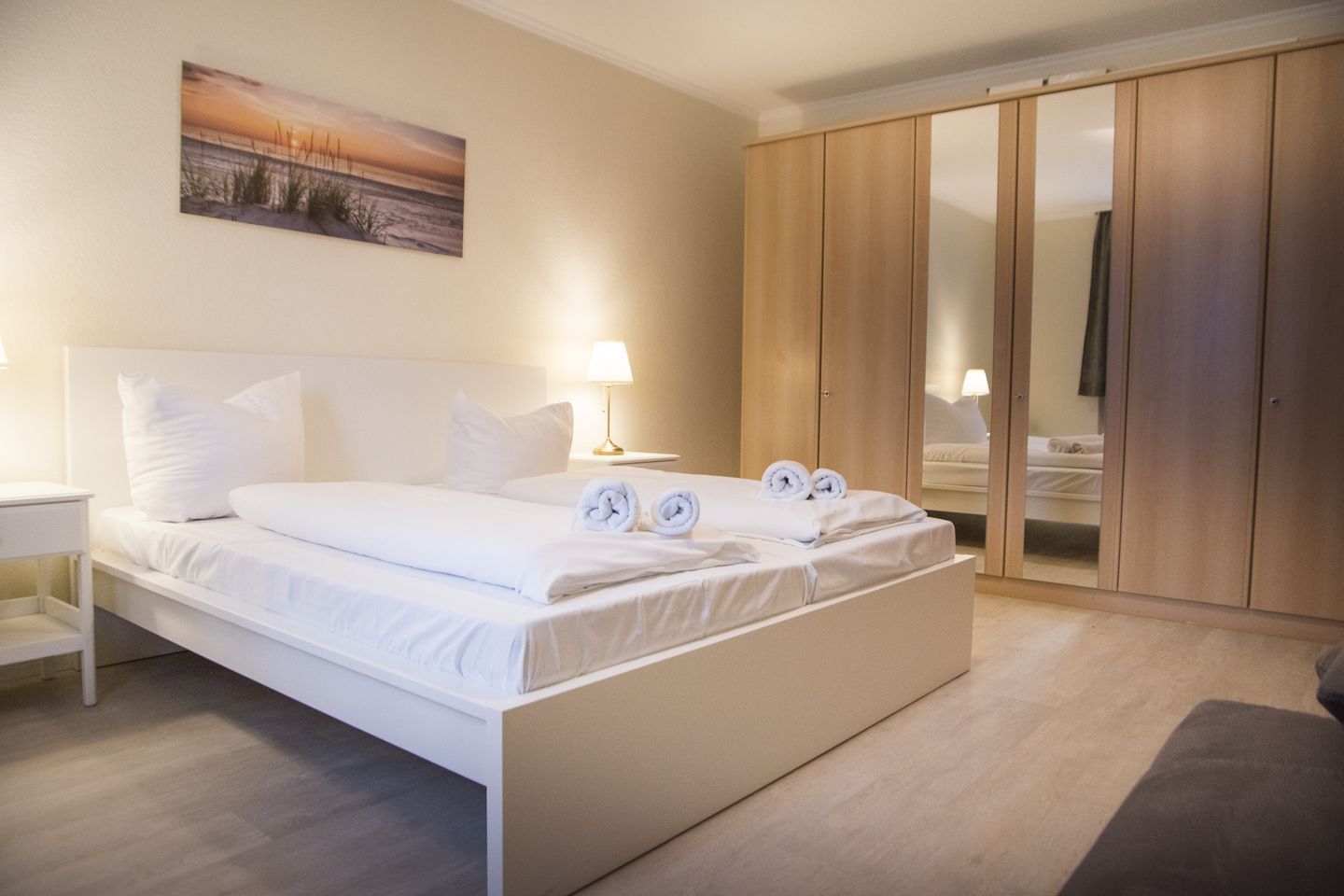 Ein Hotelzimmer mit einem großen Bett, einem Nachttisch, einer Lampe, einem Kleiderschrank und einem Gemälde an der Wand.