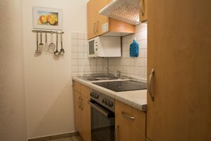 Eine Küche mit Herd, Backofen, Spüle und einem Küchenutensilienhalter.