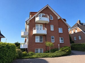 A multi-story residential building with balconies, a brick facade, and a clear sky.