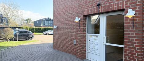 A brick building with a white door, a mailbox, and a lamp post.