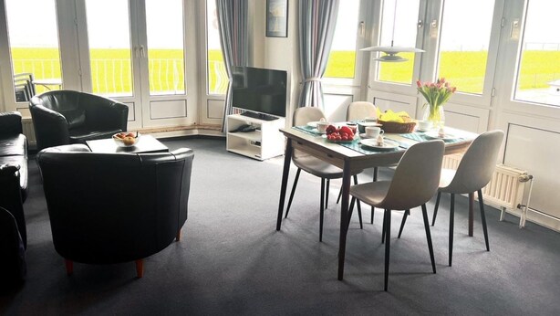 Une chambre moderne équipée d’une table à manger, de chaises, d’un téléviseur et d’un balcon avec vue.