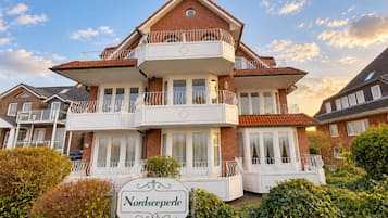 Ein mehrstöckiges Gebäude mit Balkonen, einem Schild mit der Aufschrift 'Nordseeperle' und einer Ziegel-Fassade.