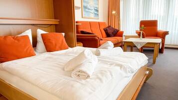 Ein Hotelzimmer mit einem Bett, zwei orangefarbenen Sesseln, einem kleinen Tisch und einem Gemälde an der Wand.