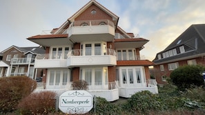 A multi-story building with balconies, a sign reading 'Nordseepferle,' and a brick facade.