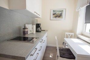 A modern kitchen with a built-in stove, white cabinets, and a coffee maker.