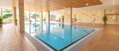 A large indoor swimming pool with a tiled floor and a wooden ceiling.