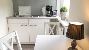 Une petite cuisine équipée d’un évier, d’une machine à café et d’une plante en pot.