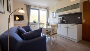 Un espace de vie compact comprenant un canapé, une table à manger et une kitchenette.