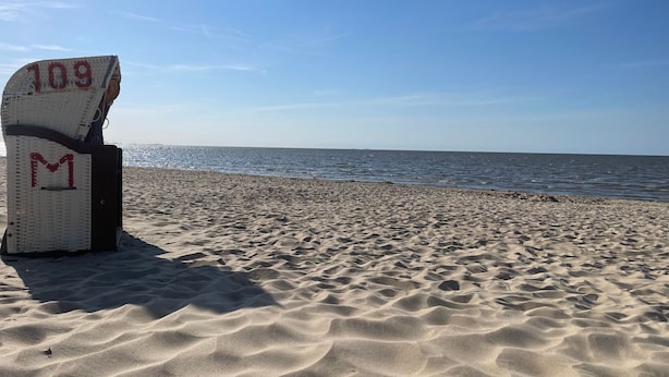 Une plage avec une chaise portant le numéro « 109 M » et une vue dégagée sur l’océan.