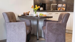 Una cocina moderna con una mesa de comedor, dos sillas tapizadas, una cafetera y una máquina de café.