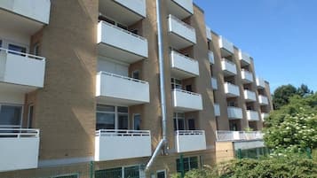 Ein mehrgeschossiges Wohngebäude mit Balkonen, einer Ziegel-Fassade und einem grünen Zaun.