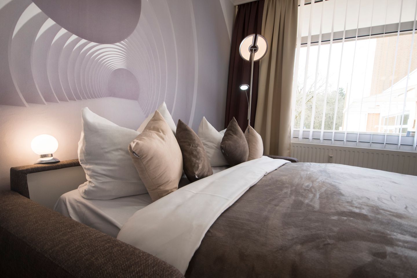 Ein modernes Schlafzimmer mit Bett, Kissen, Nachttisch und Lampe.