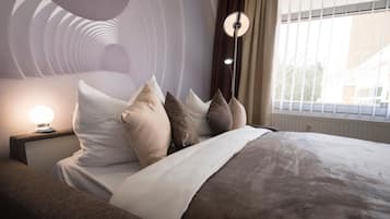 Ein modernes Schlafzimmer mit Bett, Kissen, Nachttisch und Lampe.
