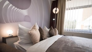 Une chambre à coucher moderne avec un lit, des oreillers, une table de chevet et une lampe.