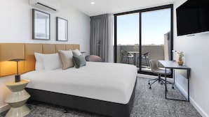 A modern hotel room with a large bed, a desk, and a balcony with a view. - Punthill Essendon North (Essendon)