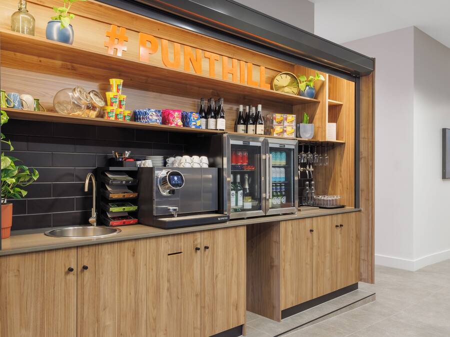 Una kitchenette moderna con una cafetera, botellas de vino y un cartel que dice 'PUNTHILL'.