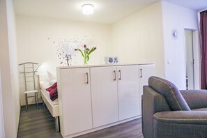 Quarto pequeno e compacto, com cama, sofá, cozinha compacta com geladeira e armário.
