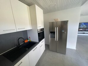 A modern kitchen with white cabinets, a black countertop, and a stainless steel refrigerator.